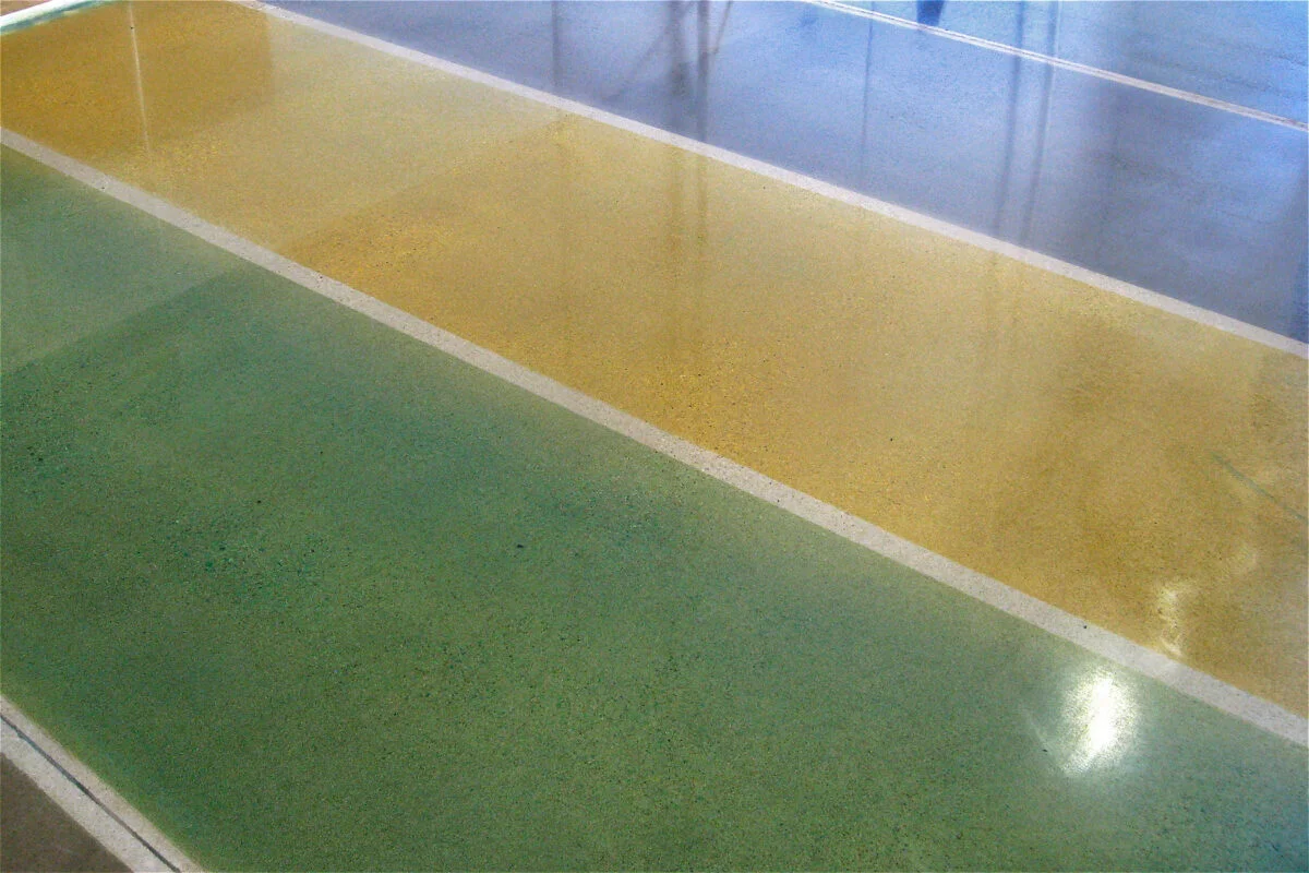 Piso decorativo con tintes verde y amarillo dorado en hormigón pulido